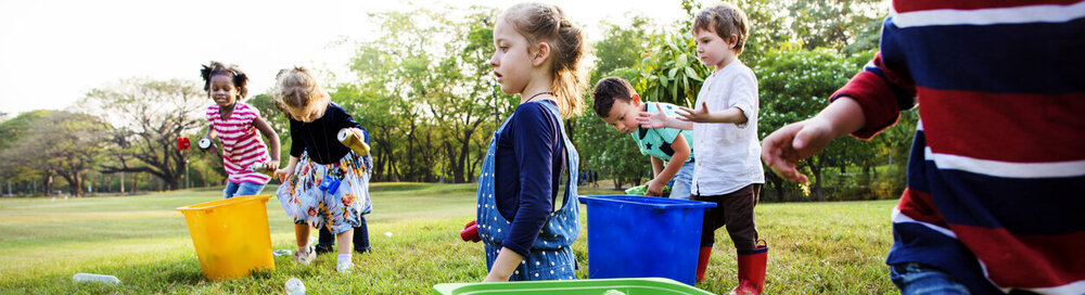 © iStock.com/Rawpixel Freiwillige Kinder nehmen einen Müll, um Mülleimer zu papieren