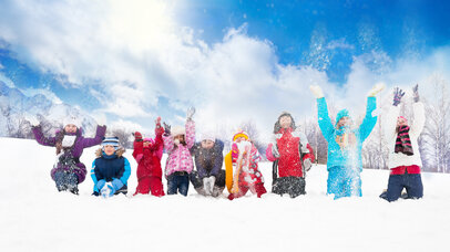 © iStock.com/SerrNovik Große Gruppe von unterschiedlich aussehenden Kindern, Jungen und Mädchen, die zusammen in einer Reihe sitzend Schnee in die Luft werfen