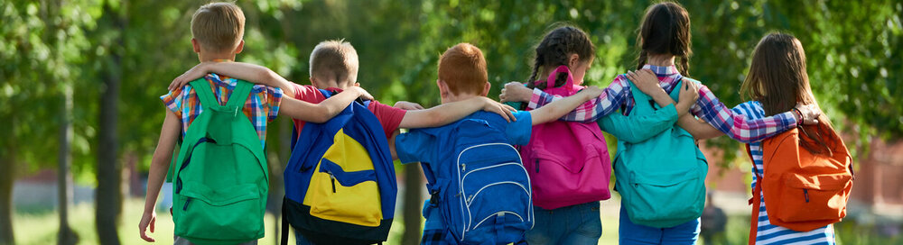 © iStock.com/mediaphotos School Freunden, Arm in Arm von hinten mit Rucksäcken