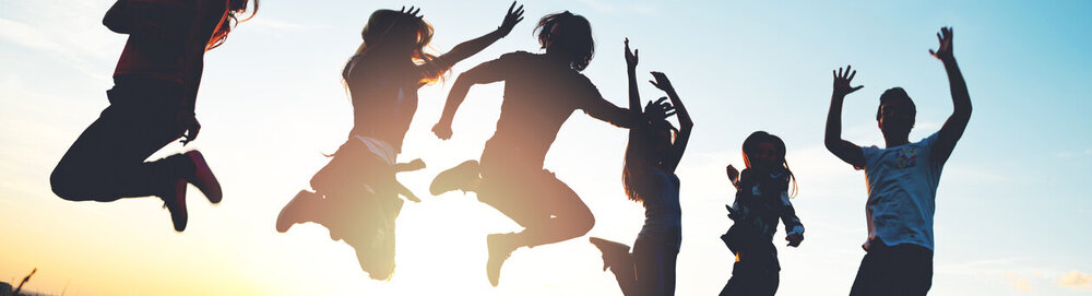 © iStock.com/Tijana87 Gruppe von Menschen, die im Freien springen; Sonnenuntergang