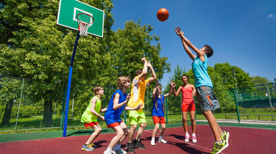 © iStock.com/SerrNovik Teenager spielen basketball-Spiel zusammen