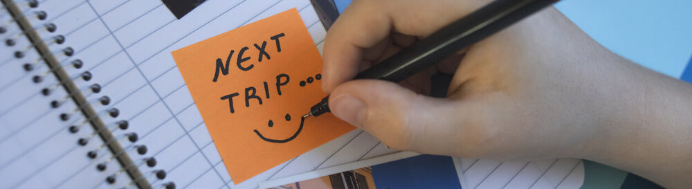 © iStock.com/portishead1 Junge Person, die Haftnotizen verwendet, um ein handgefertigtes Reisefotoalbum oder ein Sammelalbum zu erstellen